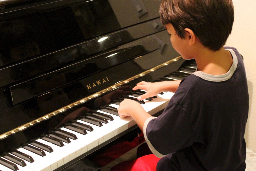 Bambino di spalle che suona il pianoforte